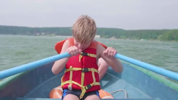 De man drijft op de boot. Tiener opereert zelfstandig een boot met de hulp van de roeiriemen. Extreme sporten — Stockvideo