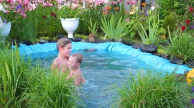 Çocuk bir sıcak yaz gününde küçük bir denizinde yüzerim. Bahçe, çiçek ve bitki göl çevresinde. Mutlu çocukluk