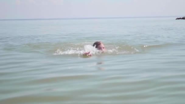 Szczęśliwe dziecko uwielbia pływać w morzu. Woda rozpylana, gorący letni dzień — Wideo stockowe