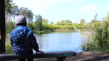 Çocuğun yakın göl parkta bir bankta oturur. Temiz havada yürüyüşler