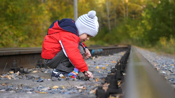 Μοναχικό αγόρι παίζει σχετικά με τις σιδηροδρομικές γραμμές. Επικίνδυνα παιχνίδια και την ψυχαγωγία. Ζεστή ημέρα του φθινοπώρου. — Φωτογραφία Αρχείου