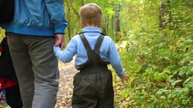 Genç bir baba çocuğunu Sonbahar Park yürür. Baba oğlu elini tutar. Sonbahar manzara