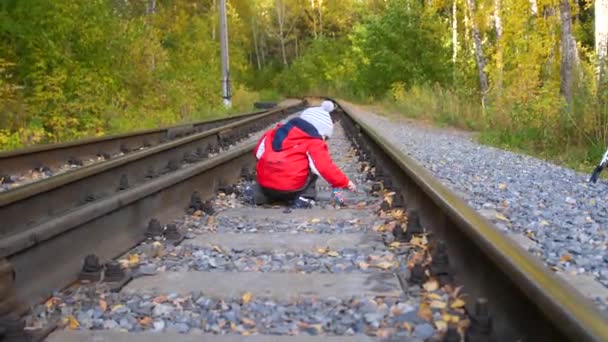 Одинокий мальчик играет на железнодорожных путях. Опасные игры и развлечения. Осенний теплый день . — стоковое видео