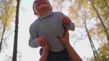 Mutlu bir aile. Anne oğlunu kucağında çocuk gülümsüyor tutar. Güneş ve gökyüzü mutlu Childs'ın yüz arka plan üzerinde