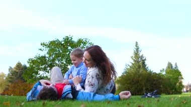 Mutlu bir aile çim üzerinde yalan. Anne ve baba oğluyla çocuk gülümsüyor oynuyor. Güneş ve gökyüzü, anne ve çocuk mutlu yüzler arka planı.