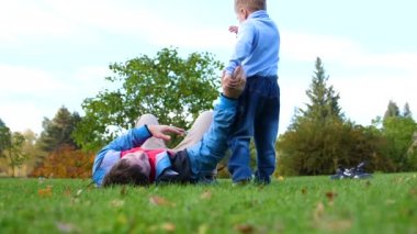 Çimenlerin üzerinde mutlu bir aile. Genç bir sevgi dolu baba başını, çocuk gülümsüyor yüksek çocuk kaldırdı. Güneş ve gökyüzü, baba ve çocuk mutlu yüzler arka planı.
