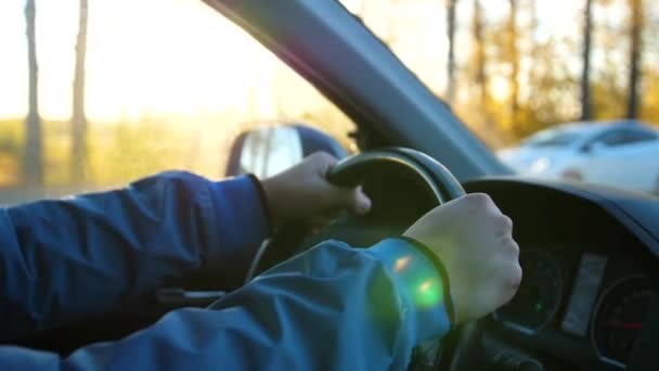 Il tipo guida un'auto in un giorno di sole. L'ora del tramonto. Mani e volante primo piano — Video Stock