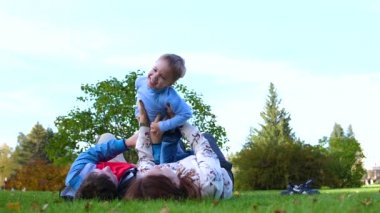 Mutlu bir aile çim üzerinde yalan. Anne ve baba oğlu onun kollarında başının çocuk gülümsüyor üzerinde tutarak. Güneş ve gökyüzü mutlu yüzler anne ve bebek zemin üzerinde.