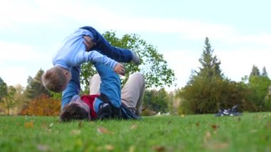 Çimenlerin üzerinde mutlu bir aile. Genç bir sevgi dolu baba başını, çocuk gülümsüyor yüksek çocuk kaldırdı. Güneş ve gökyüzü, baba ve çocuk mutlu yüzler arka planı.
