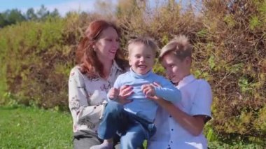 Mutlu bir aile çimenlerin üstünde dinlenme. Şefkat ve sevgi ile çocukları ile anne çalış, gülmek ve eğlenmek. Mutlu çocukluk