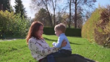 Mutlu bir aile çimenlerin üstünde dinlenme. Şefkat ve sevgi ile anne oğlu güler çocuğuyla birlikte çalış, o eğlenir. Mutlu çocukluk