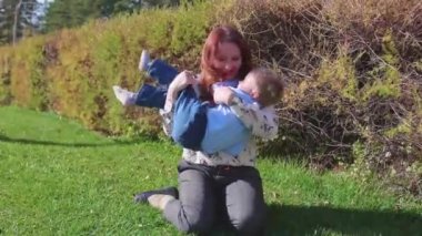 Mutlu bir aile çimenlerin üstünde dinlenme. Şefkat ve sevgi ile anne oğlu güler çocuğuyla birlikte çalış, o eğlenir. Mutlu çocukluk