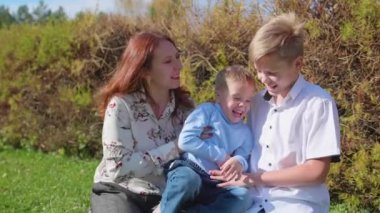 Mutlu bir aile çimenlerin üstünde dinlenme. Şefkat ve sevgi ile çocukları ile anne çalış, gülmek ve eğlenmek. Mutlu çocukluk