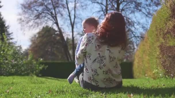 Família feliz descansando no gramado.Mãe com ternura e amor abraça seu filho, o filho ri. Infância feliz — Vídeo de Stock