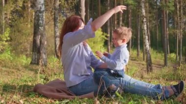 Mutlu bir aile çimenlerin üstünde dinlenme. Şefkat ve sevgi ile anne oğlu güler çocuğuyla birlikte çalış, o eğlenir. Mutlu çocukluk