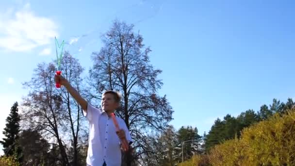休日や屋外のエンターテイメント 公園で若い男が大きなシャボン玉を作る — ストック動画