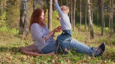 Mutlu bir aile çimenlerin üstünde dinlenme. Şefkat ve sevgi ile anne oğlu güler çocuğuyla birlikte çalış, o eğlenir. Mutlu çocukluk