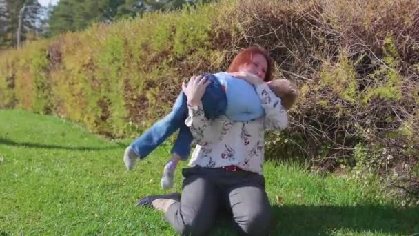 Šťastná rodina odpočívat na trávníku. Matka s něhou a láskou si hraje s její dítě, syn se směje, má zábavu. Šťastné dětství — Stock video