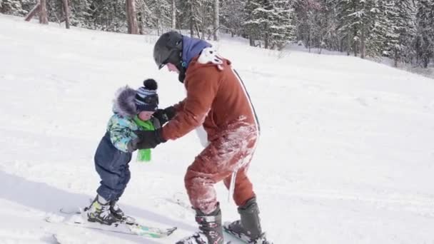 Дитина вчиться кататися на лижах з інструктором. Гірськолижний курорт. Активний спорт — стокове відео