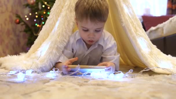 クリスマス ライトが付いているテント子供部屋でスマート フォンを遊ぶ子。幸せな子供時代 — ストック動画