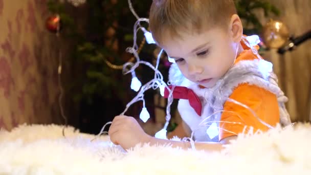 A criança brinca no quarto das crianças com uma luz de Natal, uma grinalda. Infância feliz — Vídeo de Stock