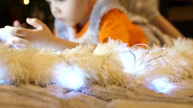 Çocuk yumuşak beyaz battaniye çocuk odasında yatıyor. Smartphone çizgi film izliyor. Noel çelenk. Mutlu çocukluk