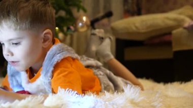 Çocuk yumuşak beyaz battaniye çocuk odasında yatıyor. Smartphone çizgi film izliyor. Noel çelenk. Mutlu çocukluk