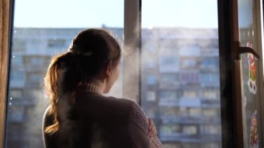 Soğuk kış günü. Kız penceresi açılır ve soğuk havada nefes.