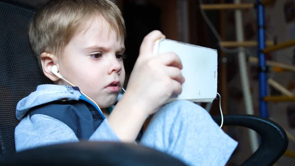 El chico escucha música a través de auriculares. En la habitación de los niños el niño disfruta de la música —  Fotos de Stock