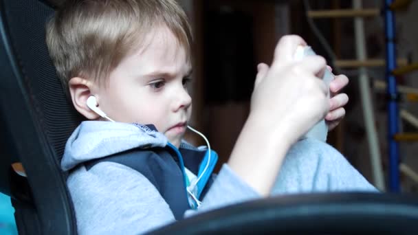 De jongen luistert naar muziek via de hoofdtelefoon. In de kinderkamer het kind geniet van muziek — Stockvideo