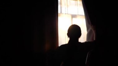 Kız sabah pencereye gider, perdeleri açar. Güneş ışınları camı delip geçmek ve Oda sabah ışık ile aydınlatmak