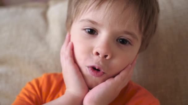 Un hermoso niño mira a la cámara y sonríe — Vídeo de stock