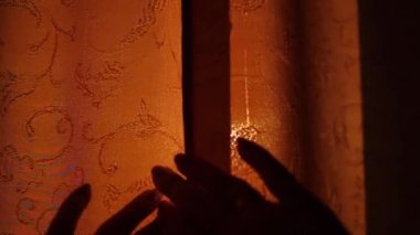 Kız sabahın erken saatlerinde perdeleri açar. Güneş ışınları pencere ve parmak geçmek