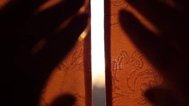 Kız sabahın erken saatlerinde perdeleri açar. Güneş ışınları pencere ve parmak geçmek