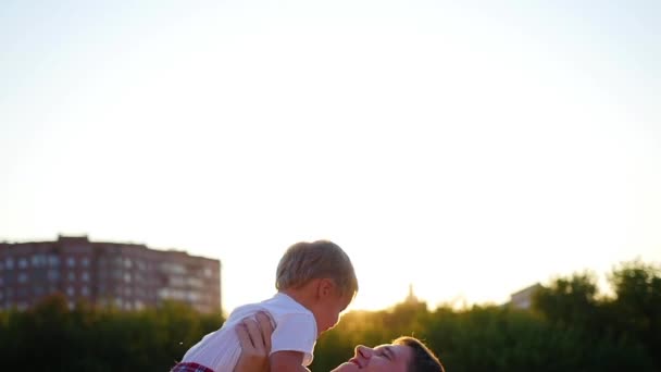 Slow-motion. een jonge vader zijn lachende baby overgeven in de lucht. Outdoor recreatie — Stockvideo