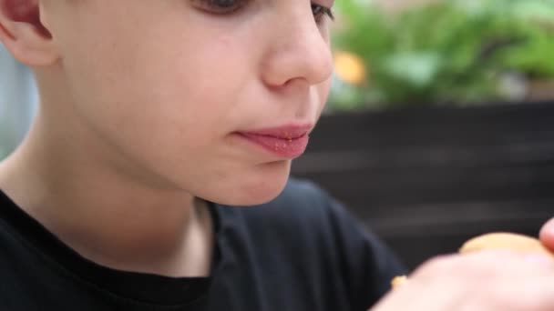 Ребенок ест булочку с котлетой и сыром в ресторане быстрого питания — стоковое видео