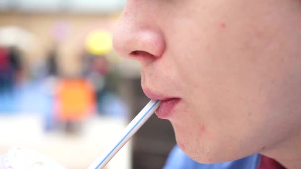 Een man in een fast food restaurant drinkt een koolzuurhoudende zoete drank door een buis. Mond close-up — Stockvideo
