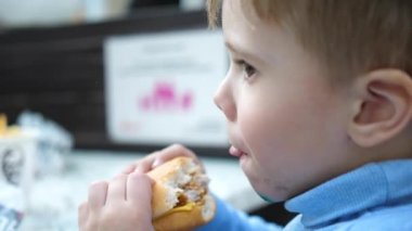 Bir çocuk bir pirzola ve peynirli çörek bir fast food Restoran yiyor.