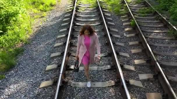 Una ragazza che cammina sui binari della ferrovia. Escursioni nel parco . — Video Stock