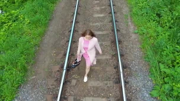 Молода дівчина ходить по залізничних коліях. Походи в парк . — стокове відео
