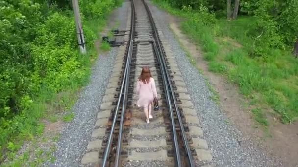 A young girl walking on the railroad tracks. Hiking in the park. — Stock Video