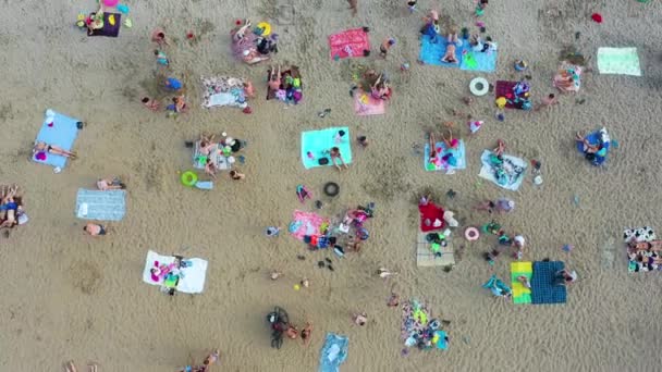 Felülnézet a strand, felvázoló színes napernyők és az emberek pihentető egy nyári napon. Forró nap, sok ember napozik és úszik — Stock videók