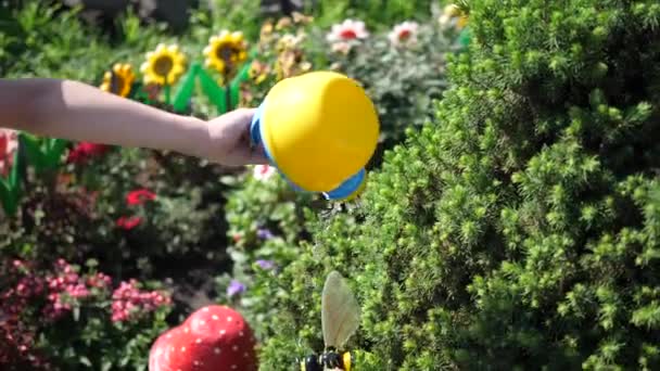 Ein Kind mit einer kleinen Gießkanne, die einen Blumengarten gießt. Junggärtner. — Stockvideo