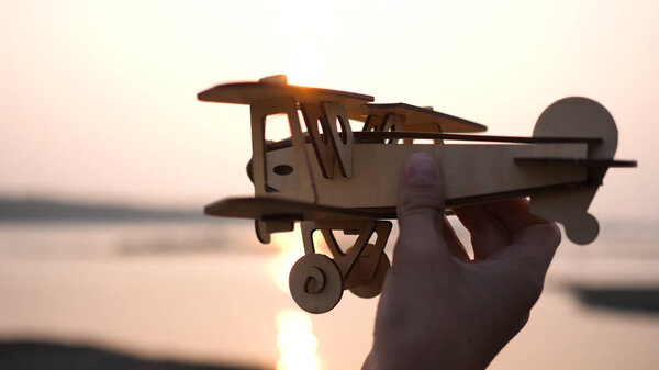 the child holds a plane in his hand against the setting sun, simulates the flight. Close up