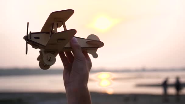 Barnet håller ett plan i handen mot solnedgången, simulerar flygningen. Närbild — Stockvideo