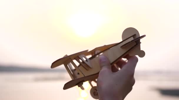 The child holds a plane in his hand against the setting sun, simulates the flight. Close up — Stock Video