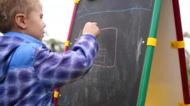 Genç sanatçı Yönetim Kurulu'na çizer. Çiçekler ve yeşillikarasında açık havada bir çocuk Kurulu tebeşir ile çocuk resimleri çizer.
