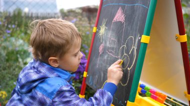 Genç sanatçı Yönetim Kurulu'na çizer. Çiçekler ve yeşillikarasında açık havada bir çocuk Kurulu tebeşir ile çocuk resimleri çizer.