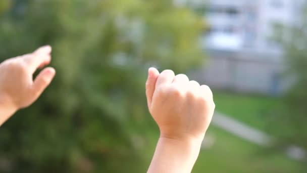 Barnet står vid fönstret och viftar med händerna. Närbild av hand — Stockvideo