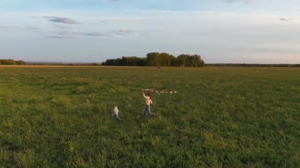 The mother and boy run with a kite on a green field. Laughter and joy, festive mood. Autumn,Sunset — Stock Video